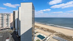 A high-rise hotel with a pool area and a beach view.