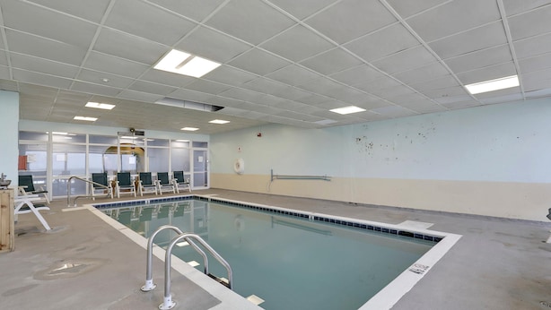 A swimming pool with a tiled deck, a lifeguard chair, and a pool ladder.