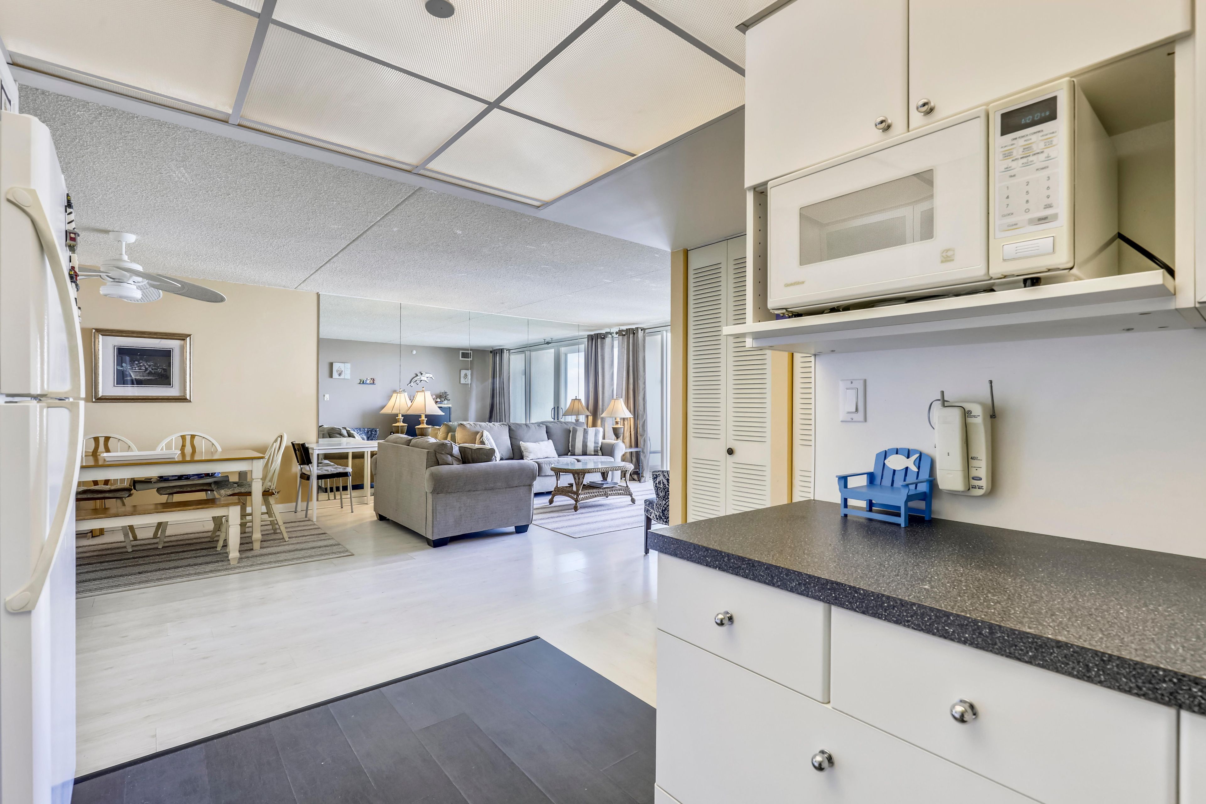 Una cocina moderna con microondas, un comedor con mesa y sillas, y una sala de estar con sofá y una mesa de centro.
