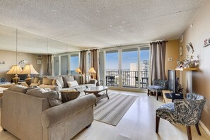 A spacious living room with a large sofa, a coffee table, and a patterned armchair.