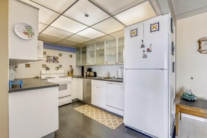 A modern kitchen with white cabinets, a built-in oven, a refrigerator, and a coffee maker.