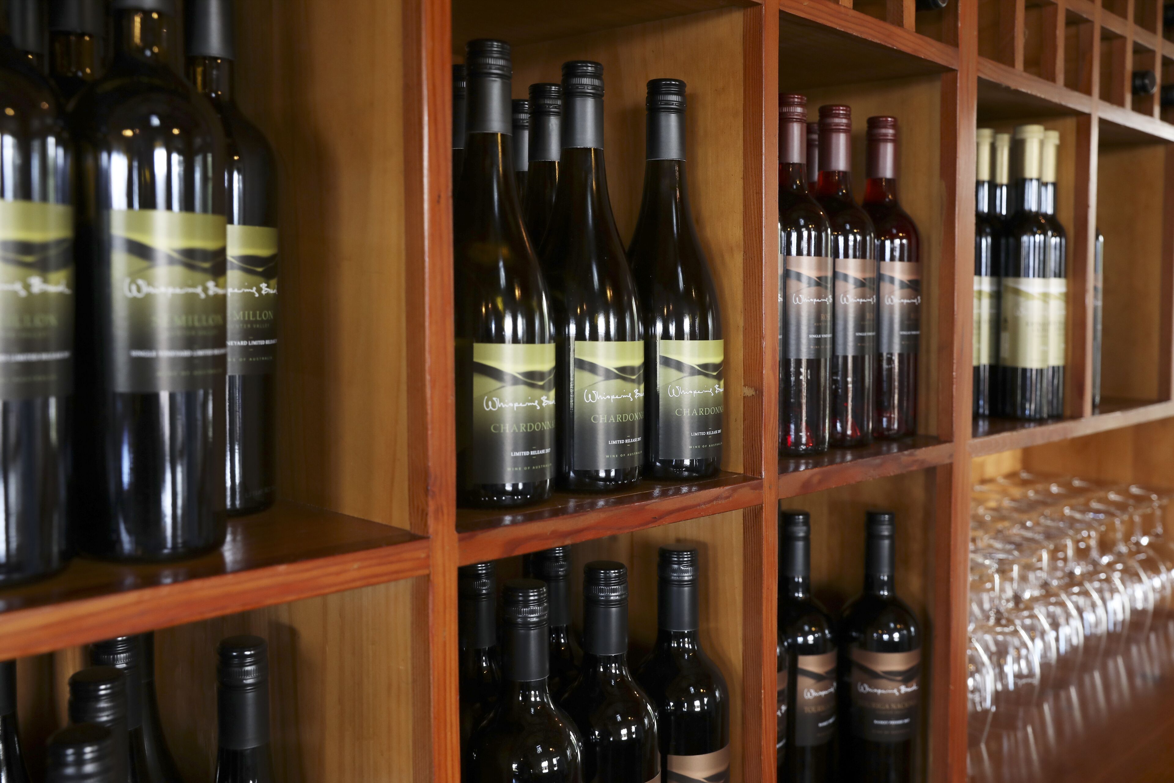 A wine rack with various bottles of wine and empty wine glasses.