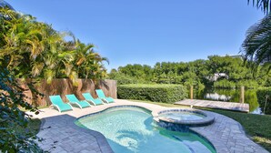 A swimming pool with a hot tub, surrounded by a wooden deck and lounge chairs. - 1 Block to Beach on Private Lake Heated Pool, SPA  6937 Holmes Blvd. (Holmes Beach)