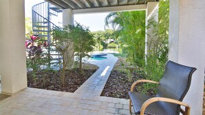 A covered patio with a pool, surrounded by plants and a spiral staircase. - 1 Block to Beach on Private Lake Heated Pool, SPA  6937 Holmes Blvd. (Holmes Beach)