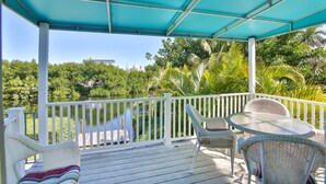 A covered outdoor deck with wicker furniture and a view of a lake and greenery. - 1 Block to Beach on Private Lake Heated Pool, SPA  6937 Holmes Blvd. (Holmes Beach)