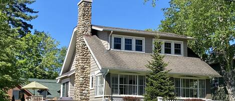 A two-story house with a stone chimney, white picket fence, and a well-maintained lawn.