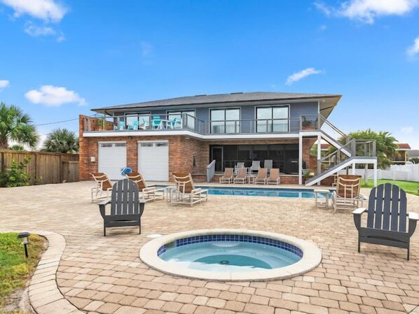Une maison à deux étages avec une piscine, un espace salon extérieur et un jacuzzi.