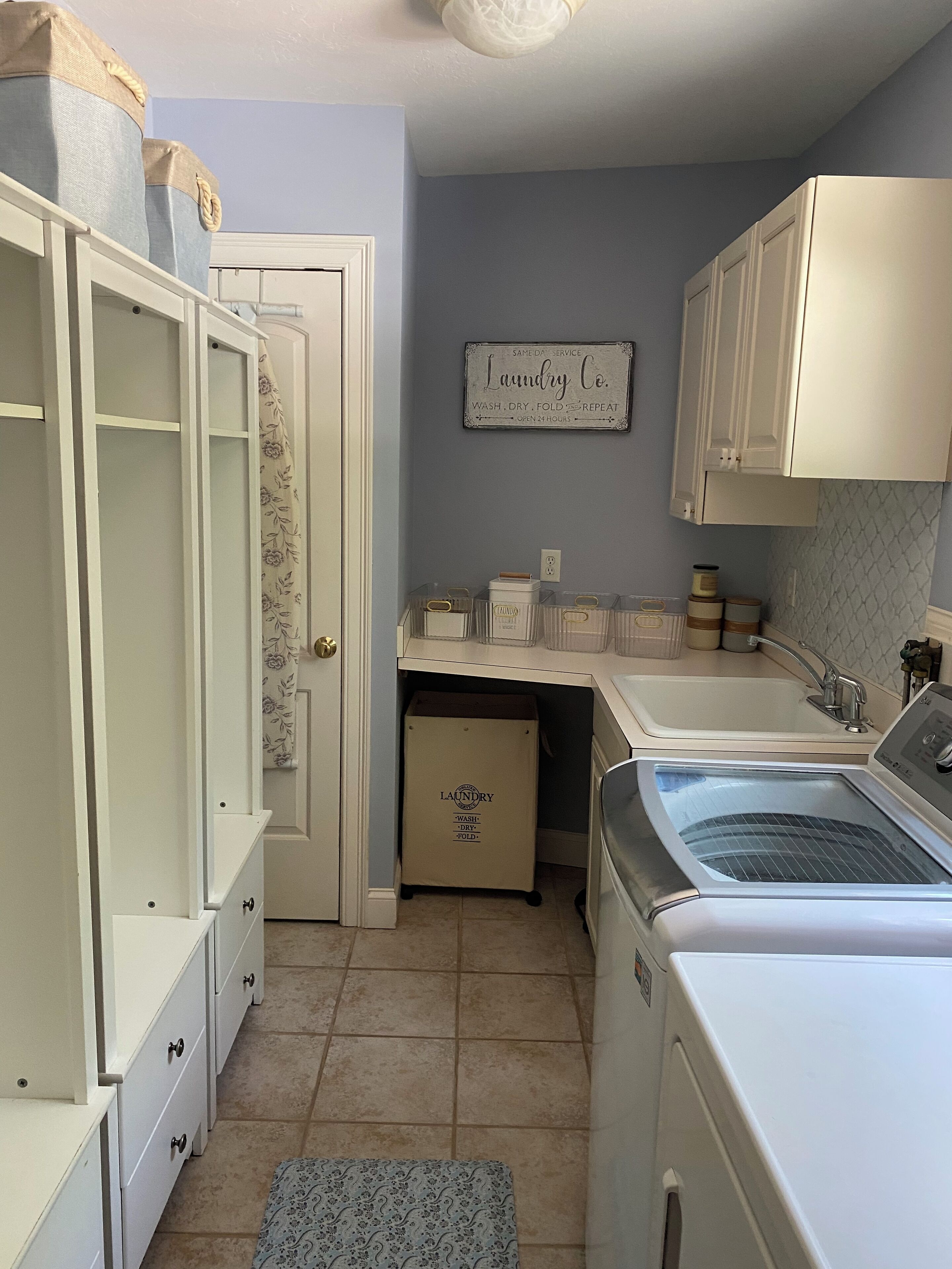 A laundry room with a washing machine, a drying machine, a sink, and a cabinet.