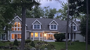Une maison à deux étages avec un porche à l’avant, de grandes fenêtres et une pelouse bien entretenue.