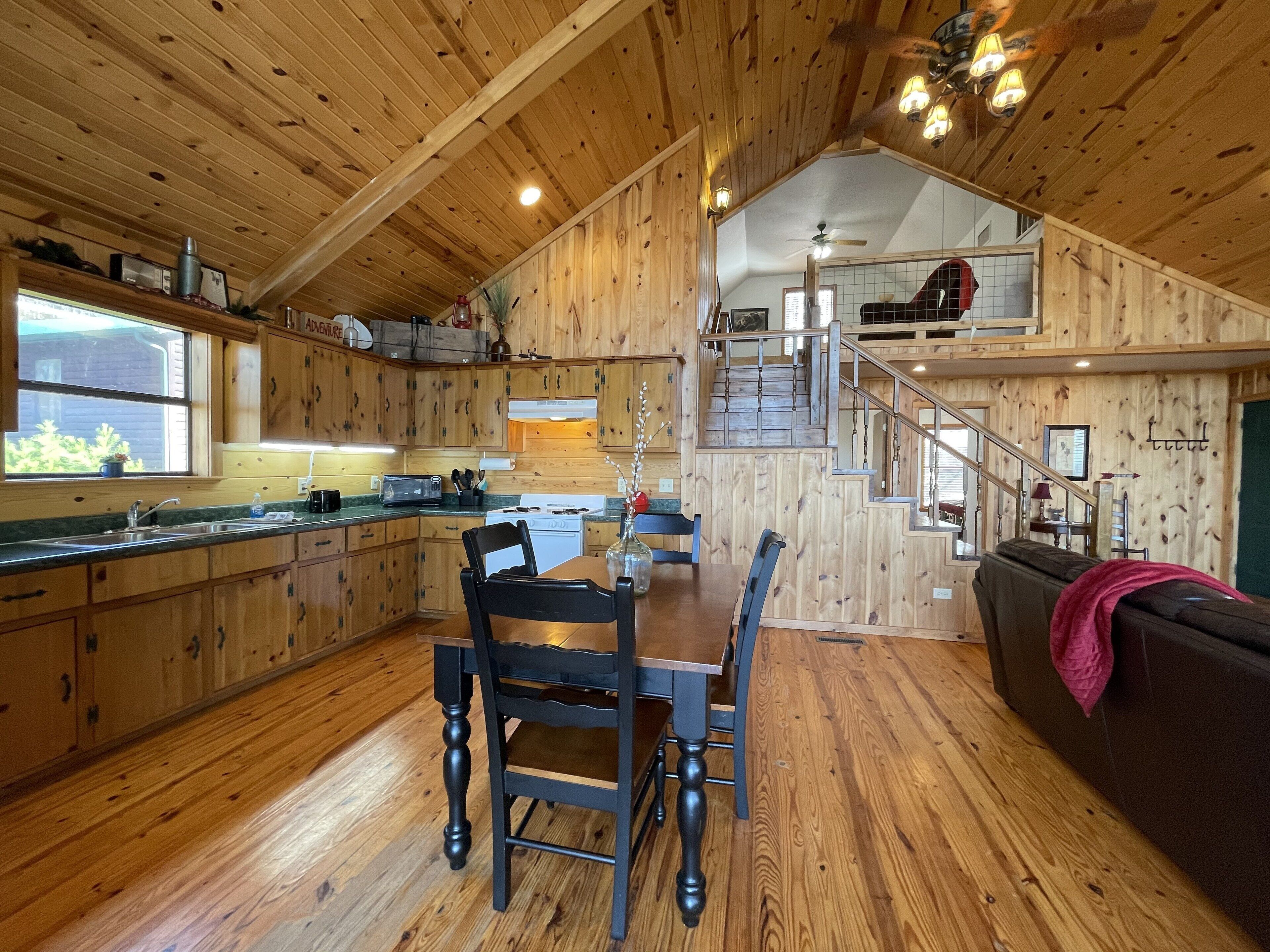 A wooden interior with a dining area, kitchen, and staircase.