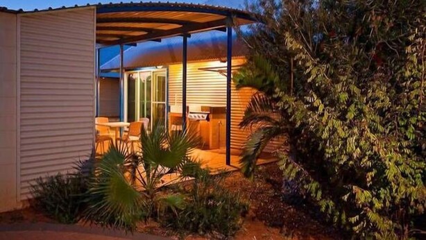 Un espace extérieur abrité, doté d’une table et de chaises, et entouré de verdure.