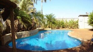 Une piscine entourée de palmiers et bordée d’un mur de briques.