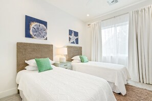 A hotel room with two beds, a headboard, a nightstand, a lamp, and artwork on the walls. - Private 7 Mile Beach Beach Club. Ocean views from Roof Terrace and Pool Pavilion (West Bay)