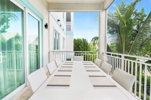 A balcony with a white table, white chairs, and a view of palm trees. - Private 7 Mile Beach Beach Club. Ocean views from Roof Terrace and Pool Pavilion (West Bay)
