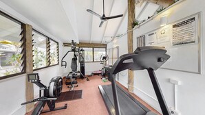 Un gimnasio con equipo de cardio, máquinas de pesas y una cinta de correr.