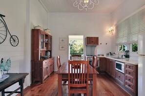 Una cocina con armarios de madera, una mesa de comedor y una araña.