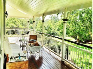 Relax on the covered porch with a garden view, featuring a table and chair.