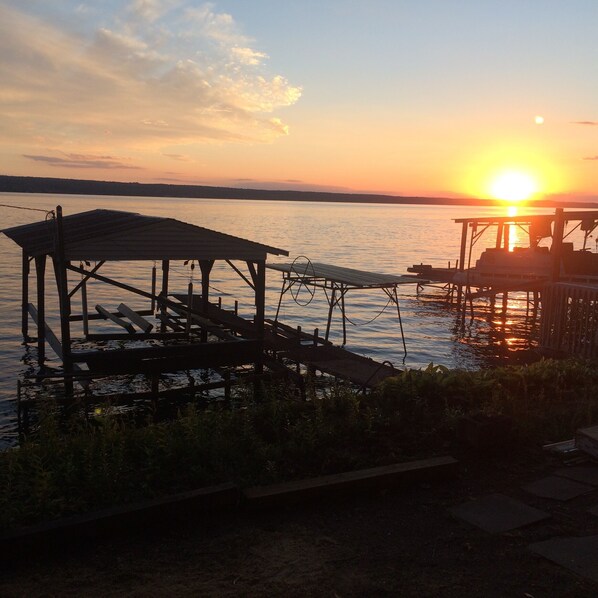 A wooden pier extending into a calm body of water during sunset.