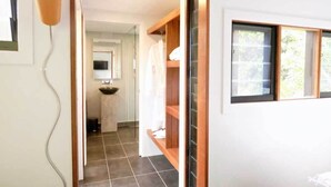 A hallway with a tiled floor, a sink, and a wooden shelf unit.