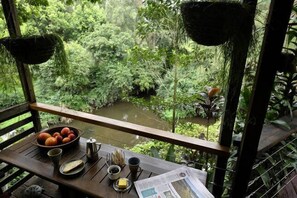 Una mesa de madera con un bol de fruta, una taza y un periódico.