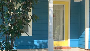 A blue house with a yellow door, a white porch column, and a sign stating "SECURED BY XFINITY Home."