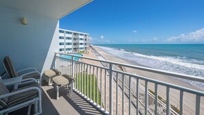 A balcony with a view of the beach and ocean, a pool, and a building with multiple floors. - Oceanfront 2BR Condo w/ Balcony & Panoramic Atlantic Views, Unit 226 (Satellite Beach)