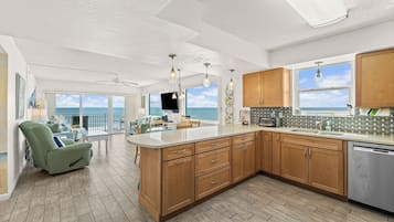 A spacious kitchen with wooden cabinets, a large island, and a view of the ocean.