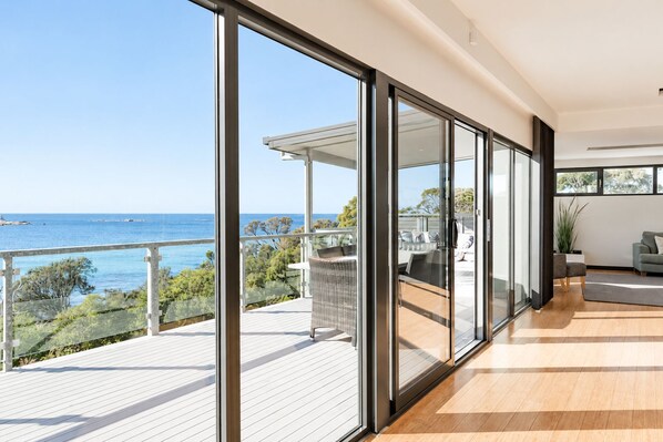 Un interior moderno con amplios ventanales correderos que dan a un balcón con vistas al mar.