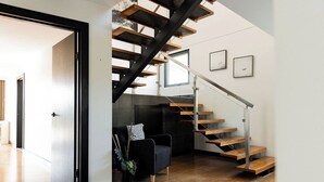 Un interior moderno con una escalera de madera, un sofá negro y un diseño minimalista.