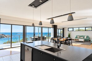 A modern kitchen with a large island, a dining area with a view, and a living space with a sofa and a view.