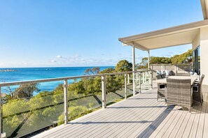 A wooden deck with a glass balustrade overlooking a coastal view.