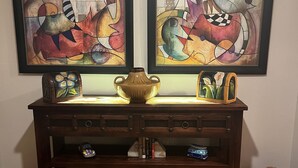 Una console de fusta amb dos quadres abstractes emmarcados, un vas i objectes decoratius.