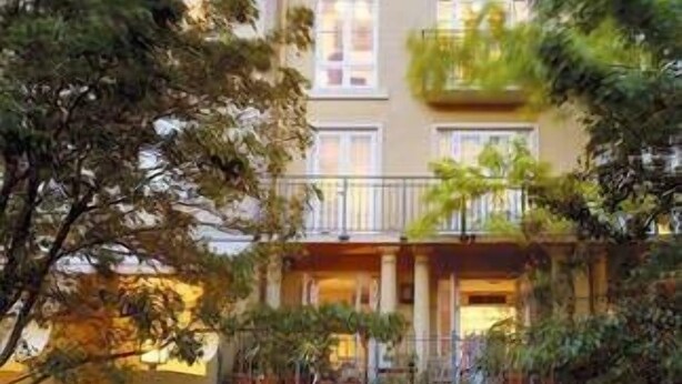 Un edificio de varios pisos con una escalera que lleva a una entrada protegida por una reja.
