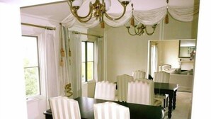 Un comedor con un espejo grande, sillas a rayas blancas, una mesa negra y un candelabro.
