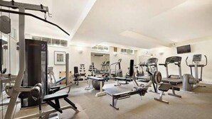 Un gimnasio espacioso con diversos equipos de ejercicio, incluyendo cintas de correr, elípticas y máquinas de pesas.
