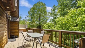 Une terrasse en bois avec une table et des chaises, un barbecue et un jacuzzi.