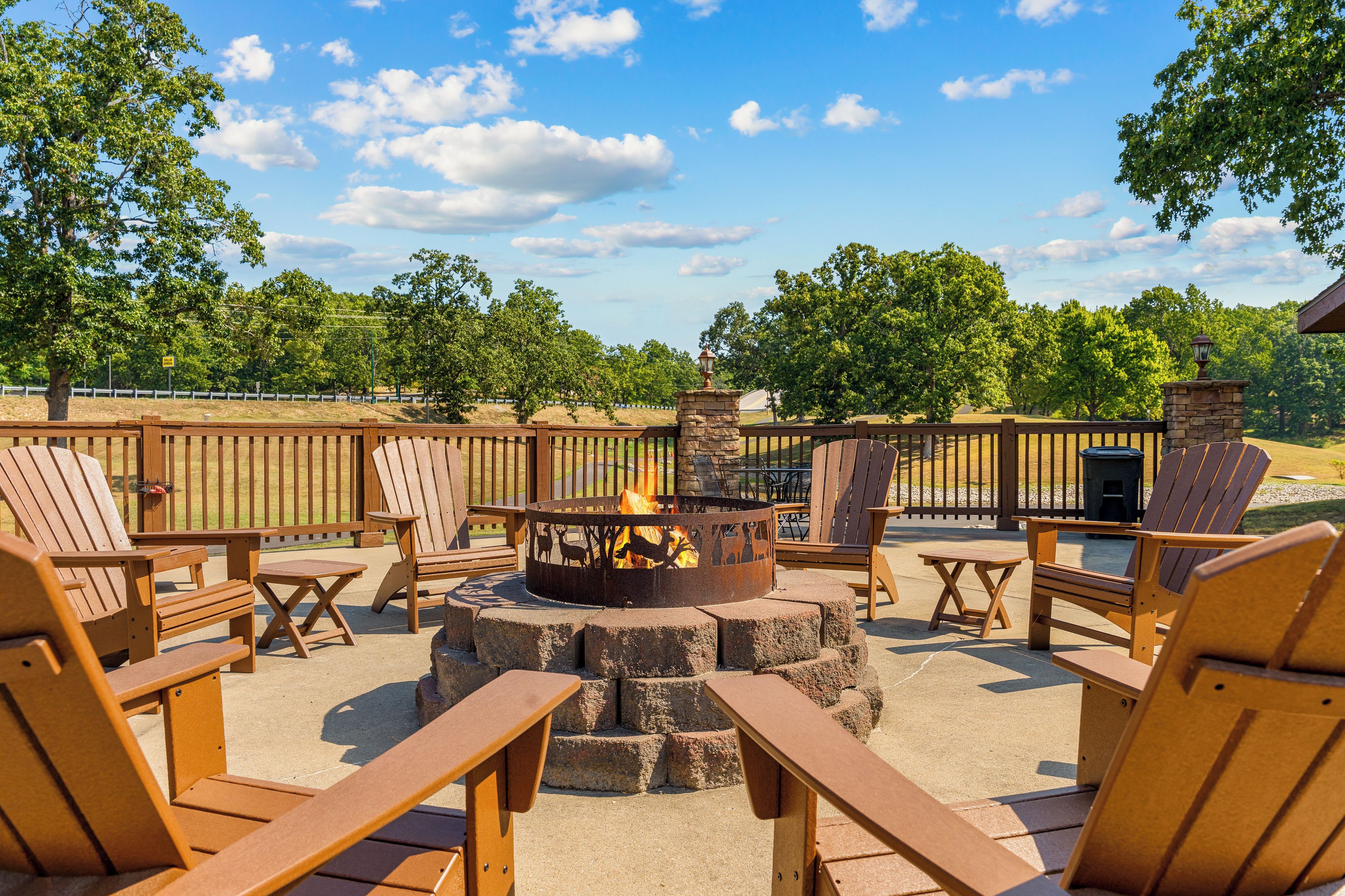 An outdoor seating area with Adirondack chairs, a fire pit, and a stone fire table.