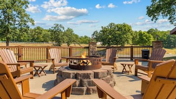 An outdoor seating area with Adirondack chairs, a fire pit, and a stone fire table.