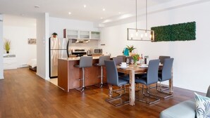 Una cocina moderna con una isla central, taburetes de bar y una mesa de comedor con sillas.