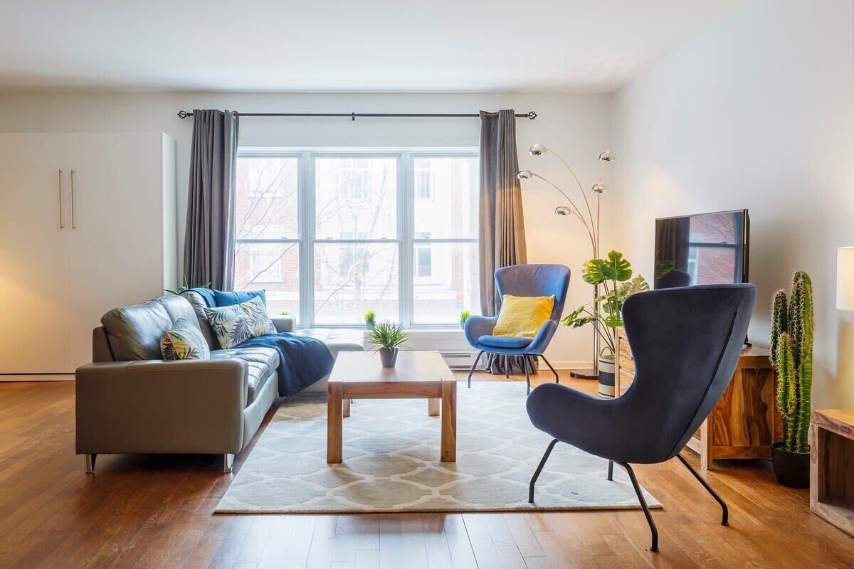 En moderne stue med sofa, lænestol, sofabord og tv.