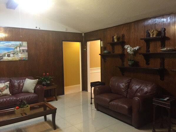 Ein Wohnzimmer mit zwei Ledersofas, einem Couchtisch und Holzregalen mit Dekoration.