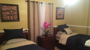 A room with two beds, a nightstand with a vase of flowers, and two framed pictures on the wall. - Super Bowl Head Quarter,NRG,Minute Maid,Convention,MedCenter,MdAnderson,Galleria (Houston)