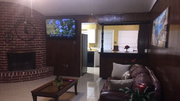 A living room with a brick fireplace, a television mounted on the wall, a leather sofa, and a coffee table. - Super Bowl Head Quarter,NRG,Minute Maid,Convention,MedCenter,MdAnderson,Galleria (Houston)
