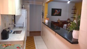 A kitchen with a sink, countertop, and a dining area with a table and chairs. - Apartment for rent in Caldas Novas (Do Turista)