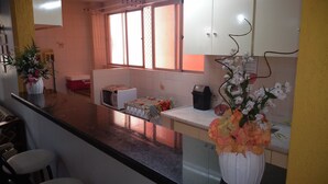 A kitchen with a microwave, a table with a tablecloth, and a flower vase. - Apartment for rent in Caldas Novas (Do Turista)