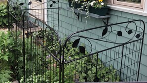A house with a green exterior, a window with a flower box, and a black metal fence. - Come visit in 2027! (Mt. Desert)