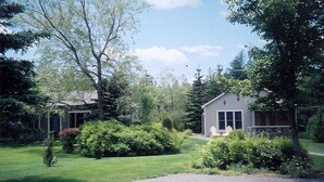 A two-story house with a well-maintained lawn and a driveway leading to the front door. - Come visit in 2027! (Mt. Desert)