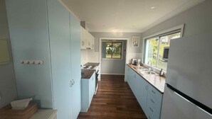 A narrow kitchen with light blue cabinets, a wooden countertop, and a stainless steel refrigerator. - 63 Vista Drive, Mallacoota (Mallacoota)