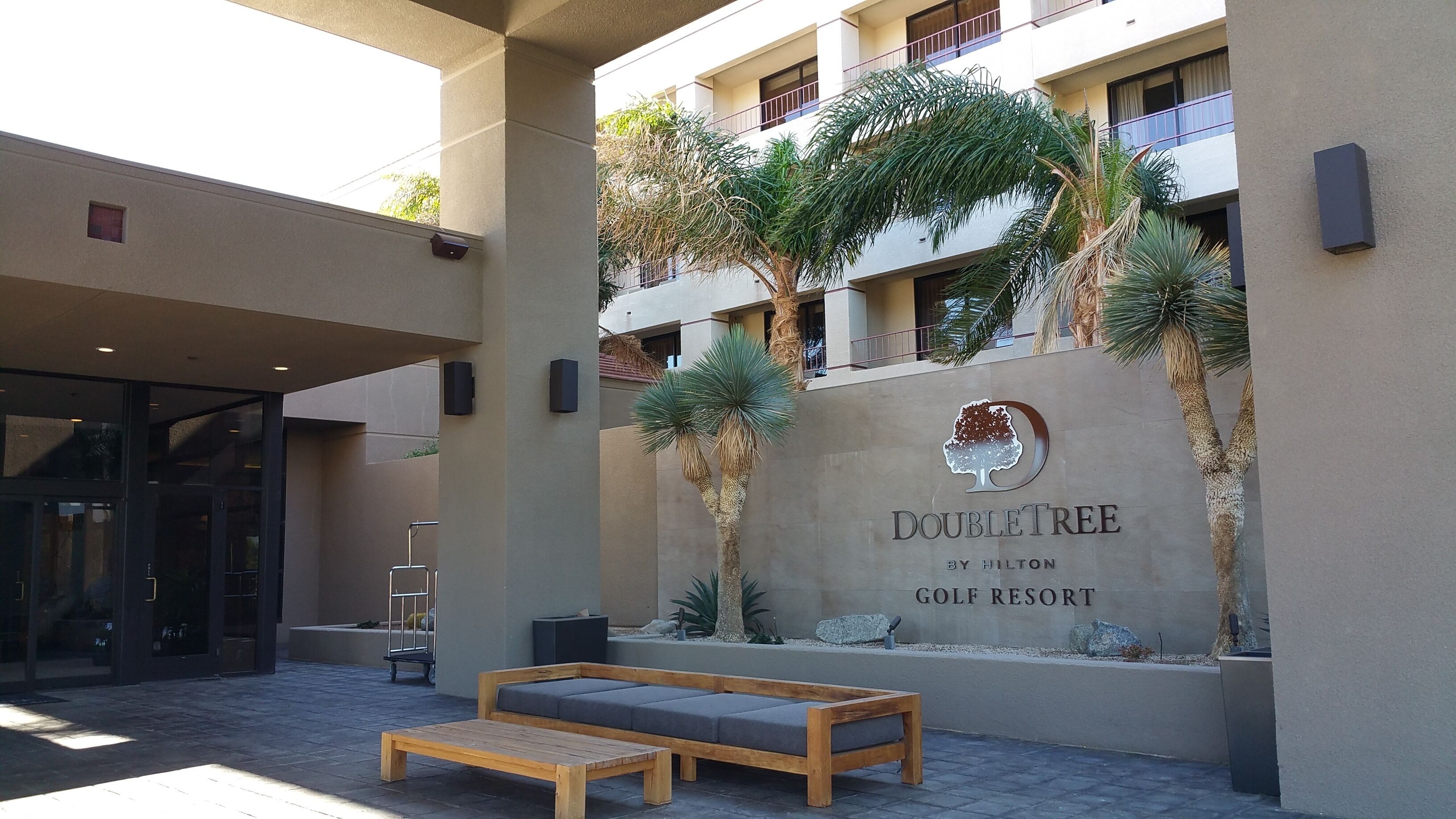 A DoubleTree by Hilton golf resort entrance with a seating area and a wall-mounted sign.