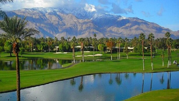 A golf course with a pond, palm trees, and mountains in the background. - Beautiful Desert Princess Resort Condo Awesome Views of Golf Course & Mountains  (Cathedral City)